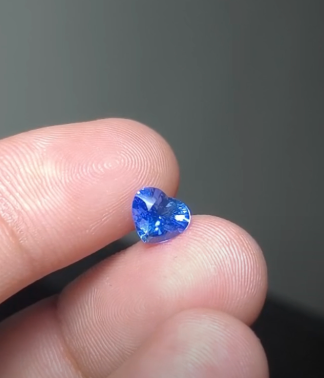 GS-000003 — 1 ct heart-shaped blue sapphire held between fingertips
