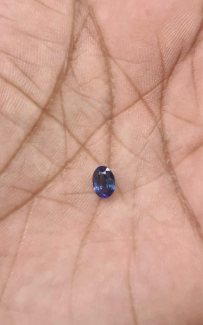 GS-000004 — owner-reported 0.8 ct blue sapphire photographed on a palm